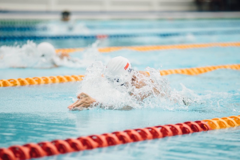 A person lane swimming in a pool, wearing a cap